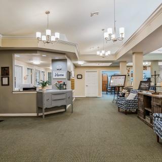 A spacious and well-lit reception area featuring modern chandeliers, comfortable seating, and a welcoming ambiance.