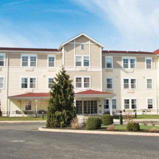 A large residential building with multiple floors, featuring a central entrance and neatly maintained surroundings.