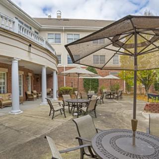 An outdoor patio area with tables, chairs, and umbrellas in front of a building.