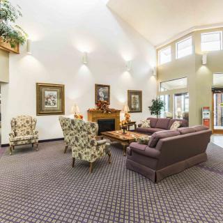 A spacious lobby with comfortable sofas and armchairs arranged around a fireplace, adorned with artwork and decorative lighting.