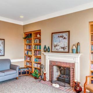 A cozy living room featuring a fireplace with artwork above, flanked by bookshelves filled with books and decorative items. A comfortable sofa is positioned to the side.
