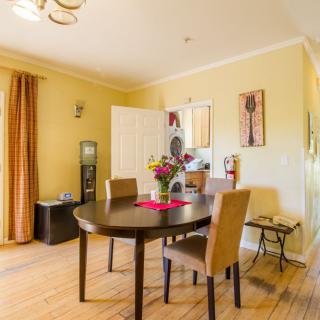 A cozy dining room with a round table and four chairs, decorated with flowers and artwork.