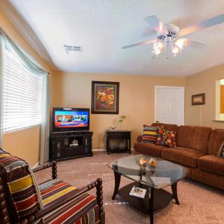 A cozy living room with a brown sofa, striped armchair, coffee table, and a TV in the corner.