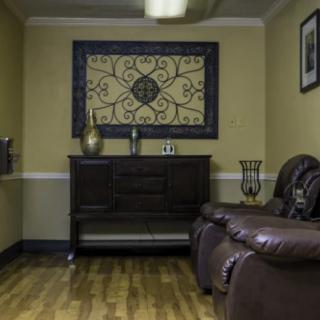 A cozy living room with a leather sofa, decorative wall art, and a wooden cabinet on a hardwood floor.