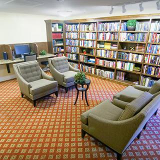 A cozy library corner with bookshelves, comfortable chairs, and a sofa.