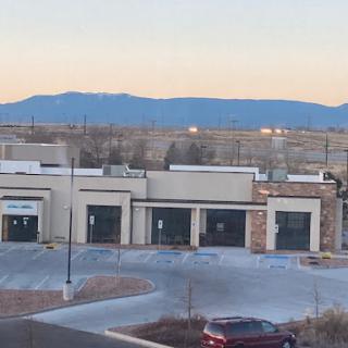 A view of a shopping center with empty storefronts and mountains in the background during sunset.
