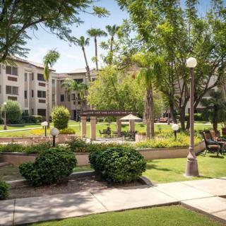A peaceful garden setting with greenery, walkways, and benches beside a building.