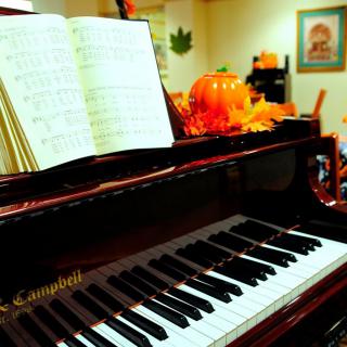 A piano adorned with autumn decorations and sheet music.