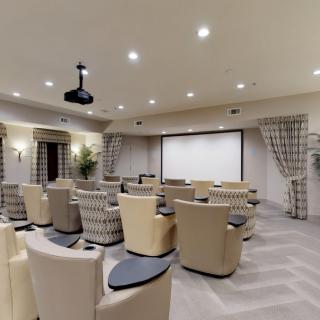 A luxurious home theater setup with comfortable recliner seats facing a large projection screen.