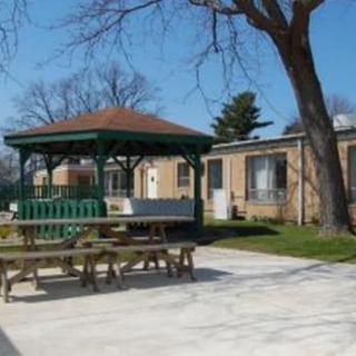 A peaceful outdoor area featuring a gazebo and picnic tables next to a building, under clear blue skies.