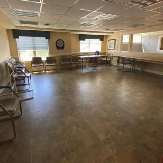 An empty meeting room with chairs along the walls and large windows.