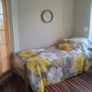 A cozy bedroom featuring a neatly made bed with floral bedding and a wall clock.
