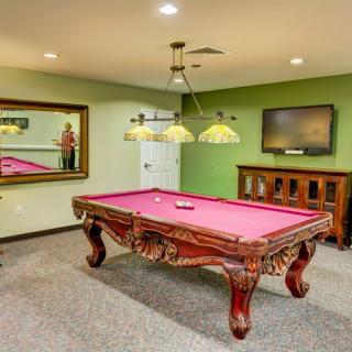 A cozy billiard room featuring a classic pool table with intricate woodwork, surrounded by elegant furnishings.