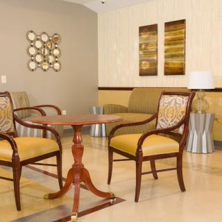A modern living room with two elegant chairs and a round wooden table, complemented by stylish wall art.