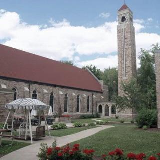 A stone church with a tall bell tower and a well-maintained garden.