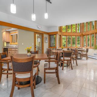 A modern dining area with wooden furniture and large windows overlooking a lush green view.