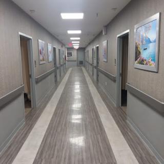 A long, well-lit corridor featuring multiple doors and decorative wall art.