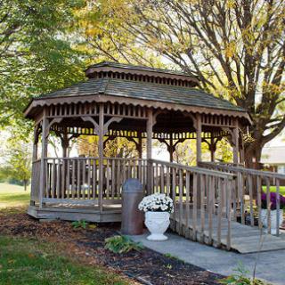 A charming wooden gazebo surrounded by autumn foliage, perfect for enjoying the outdoors.