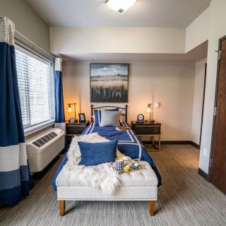 A modern bedroom with a blue and white color scheme, featuring stylish decor and natural light.