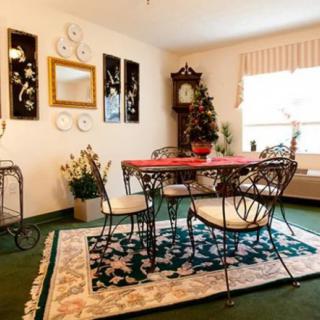 A cozy dining room with a vintage theme, featuring a wrought iron table and chairs, decorative wall art, and a grandfather clock.