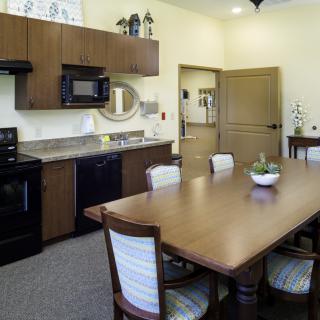 A modern kitchen and dining area featuring a wooden table with chairs, equipped with appliances like a microwave and stove.
