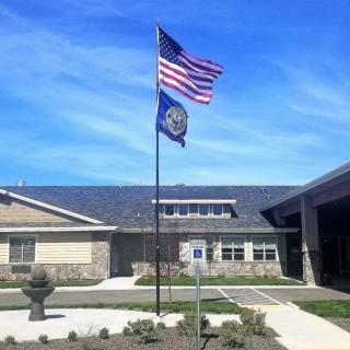 An American flag flying in front of a building under a clear blue sky.
