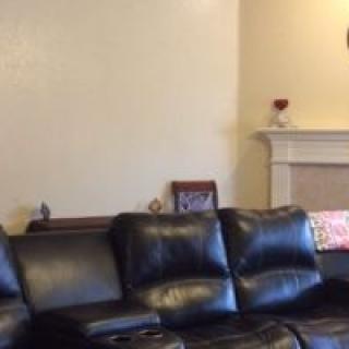 A cozy living room featuring a black leather sofa and a decorative fireplace.