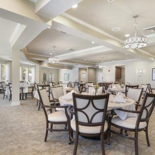 An elegant dining room with neatly arranged tables and chairs, featuring a sophisticated chandelier.
