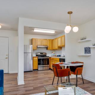 A modern open floor plan kitchen and dining area with wooden cabinets and stainless steel appliances.