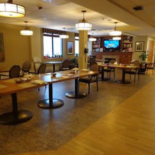 A cozy dining area featuring tables and chairs, with warm lighting and a television in the background.