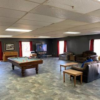 A spacious game room with a pool table, couches, and a television.