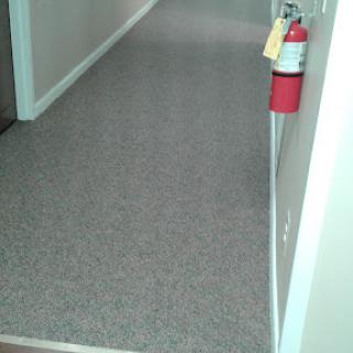 A view of a hallway featuring a fire extinguisher mounted on the wall.