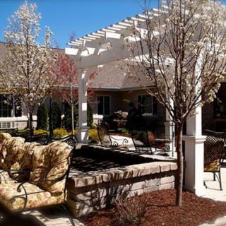 A serene patio with comfortable seating and a pergola amidst landscaped surroundings.
