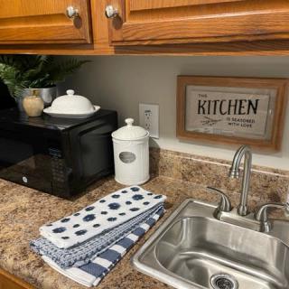 A cozy kitchen counter setup with a sink, microwave, and decorative items.