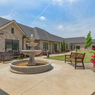 A peaceful courtyard with a fountain, benches, and landscaped garden area.