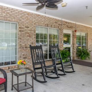 A cozy patio area with rocking chairs and a ceiling fan against a brick wall.