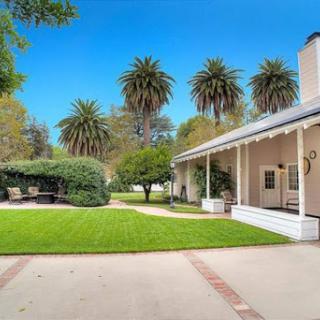 A charming house surrounded by lush greenery and palm trees, perfect for outdoor relaxation.