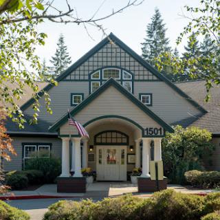 A beautifully designed entrance of a building, surrounded by lush landscaping and trees.