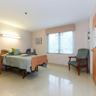 A tidy hospital room with a single bed and window.