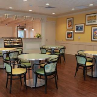 A cozy cafe with round tables and chairs, featuring artwork on the walls.