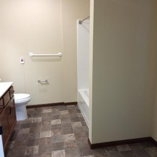 A clean and spacious bathroom with a toilet, bathtub, and sink.