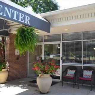 The welcoming entrance of a community center, featuring beautiful flowers and outdoor seating.