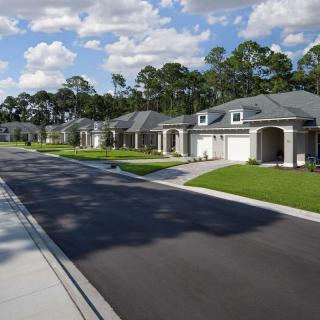 A quiet suburban street lined with modern houses on a sunny day.