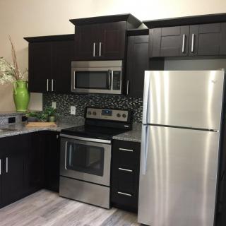 Modern kitchen with dark cabinets and stainless steel appliances.