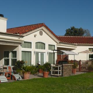 A sunny backyard with a patio and outdoor furniture, showcasing a modern house design.
