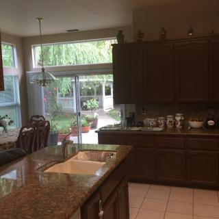 A well-lit kitchen with wooden cabinets and a large window opening to a garden view.