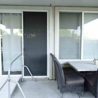 A patio area with a table and chairs next to a sliding glass door and windows.