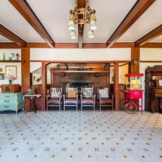 A vintage-inspired living room featuring antique furniture, a chandelier, and a popcorn machine with decorative wood beams and tile flooring.