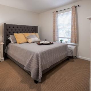 A cozy bedroom with a neatly made bed, featuring decorative pillows and warm lighting.