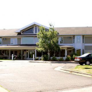 A two-story residential building with a sloped roof and a driveway in front.